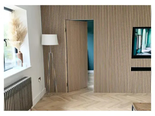 Una puerta oculta en una pared revestida de lamas de madera, una solución ingeniosa para como ocultar una puerta en una pared.