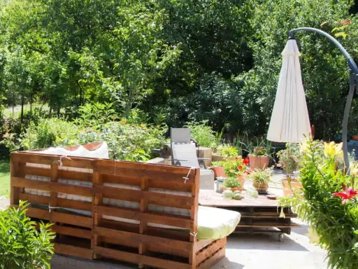 Un rincón acogedor en el jardín, con muebles de palets y plantas exuberantes. Ideal para una zona chill out.