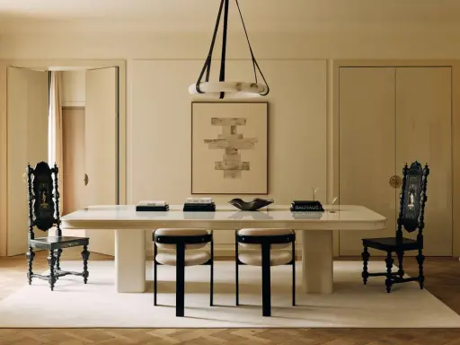 Comedor elegante con mesa blanca, sillas negras y una paleta de colores crema. Arte abstracto y cortinas suaves complementan el espacio.