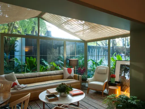 Acogedor solarium terraza con sofá a rayas, sillón, mesa de centro y exuberante vegetación.