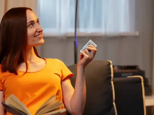 Mujer sonríe con un control remoto en mano, pensando que 800 kWh es mucho para su factura de luz.