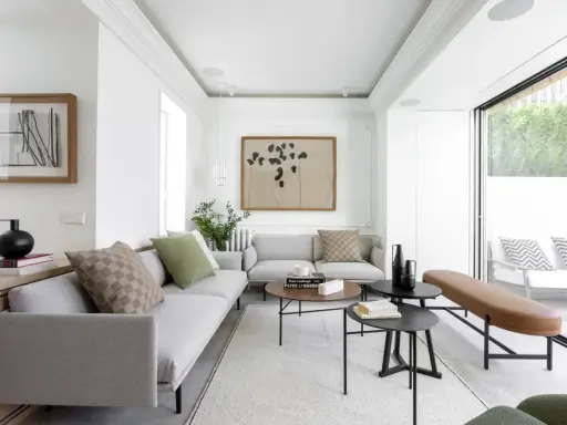 Salón moderno con sofás grises, mesas bajas y acceso directo a una terraza, creando un espacio fluido para unir terraza y salón.