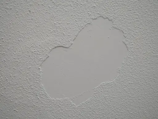 Parche de yeso liso sobre pared con gotelé, listo para lijar y unificar la textura.