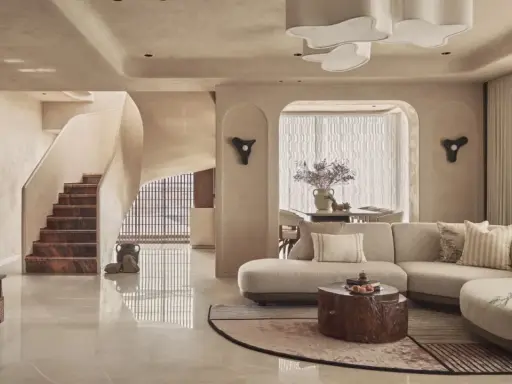 Salón con sofá curvo, mesa de centro de tronco y escaleras de mármol. Un espacio con estilo vanguardista y acabados orgánicos.