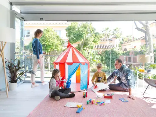 Familia divirtiéndose en una terraza decorada para niños con una carpa de circo y juegos.