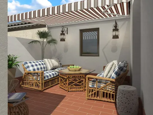 Acogedora decoracion patio interior con muebles de mimbre, cojines a cuadros y un toldo a rayas.