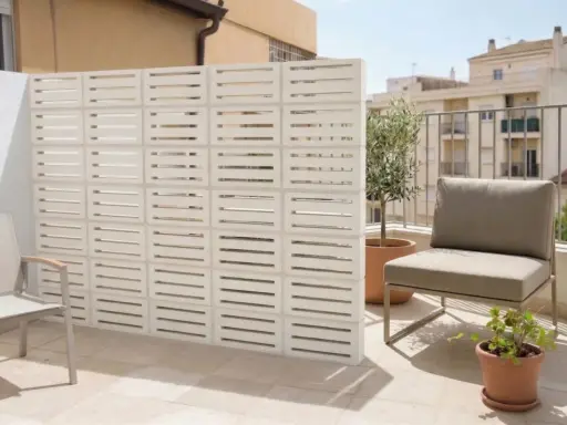 Modernos bloques de hormigón blanco crean un separador de ambiente, una de las mejores tapar balcon ideas. Un sillón y plantas completan el espacio.