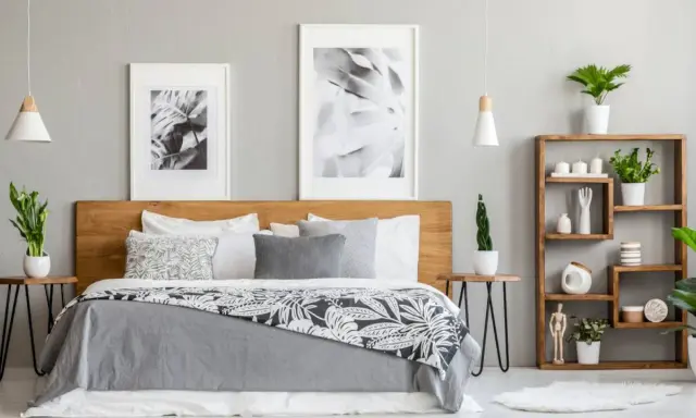 Dormitorio moderno con cama de madera, cuadros botánicos y estantería. Los tonos grises para paredes interiores crean un ambiente sereno y elegante.