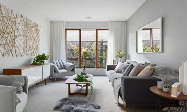 Salones en gris y beige con sofá oscuro, sillón acogedor, mesa de centro de madera y decoración natural.