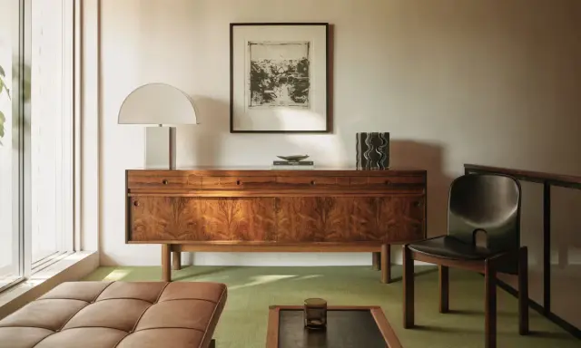 Elegante aparador de madera con **mid century decoracion**, lámpara de diseño, cuadro y silla de cuero.
