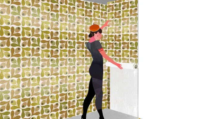 Mujer con boina naranja y vestido gris, aplicando papel pintado con patrón de olivas. Aprende como rematar papel pintado para un acabado perfecto.