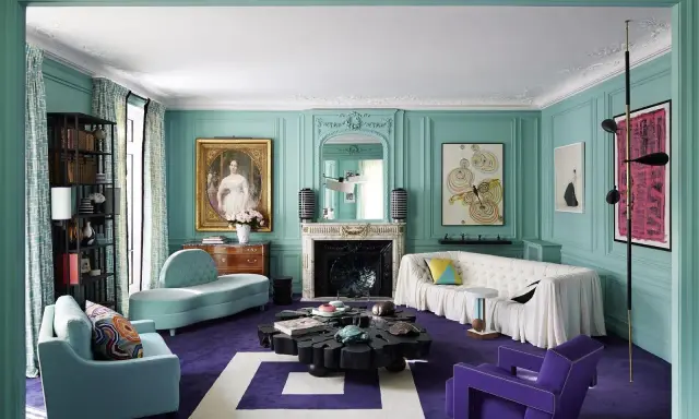 Sala de estar con paredes turquesas y alfombra morada. Muebles modernos y un retrato clásico crean un espacio amplio, ideal para aprender como pintar una habitacion para que se vea mas grande.