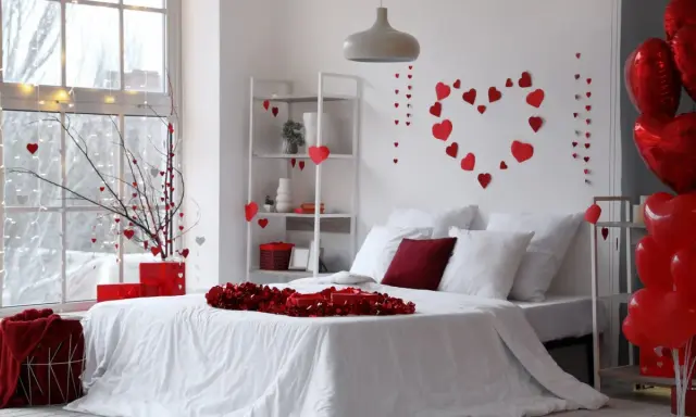 Un dormitorio decorado con un estilo romántico, lleno de corazones rojos y globos, ideal para San Valentín.