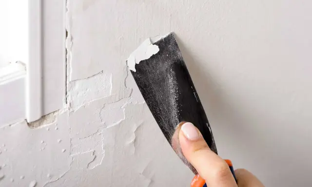 Raspando pintura vieja para preparar la pared. Paso clave para como pintar una pared ya pintada de otro color.