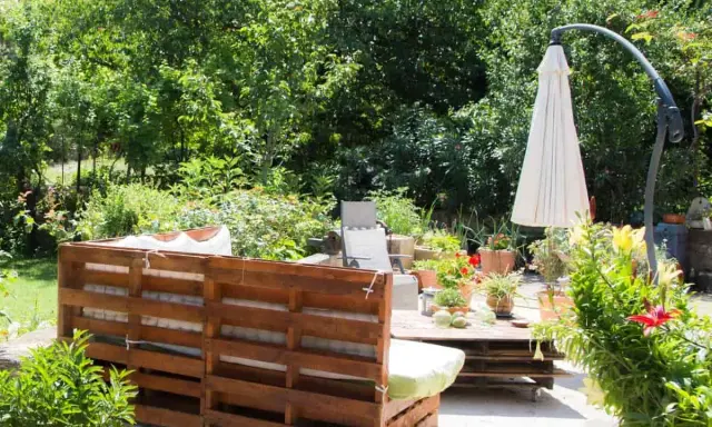 Un rincón acogedor en el jardín, con muebles de palets y plantas exuberantes. Ideal para una zona chill out.