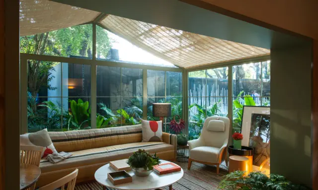 Acogedor solarium terraza con sofá a rayas, sillón, mesa de centro y exuberante vegetación.