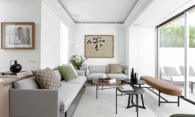 Salón moderno con sofás grises, mesas bajas y acceso directo a una terraza, creando un espacio fluido para unir terraza y salón.