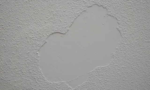 Parche de yeso liso sobre pared con gotelé, listo para lijar y unificar la textura.
