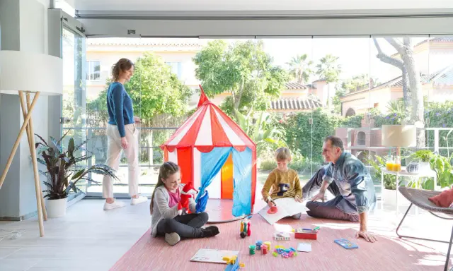 Familia divirtiéndose en una terraza decorada para niños con una carpa de circo y juegos.