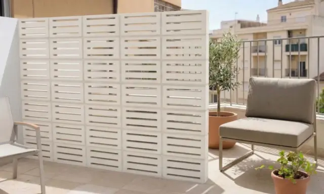 Modernos bloques de hormigón blanco crean un separador de ambiente, una de las mejores tapar balcon ideas. Un sillón y plantas completan el espacio.