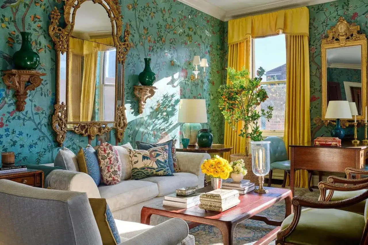 Ideas para decorar un espejo de pared: un salón con papel pintado floral, cortinas amarillas y un espejo dorado con ornamentos.