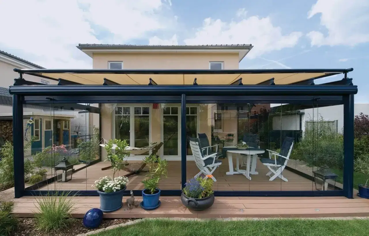 Terraza moderna con fachada de cristal y muebles de exterior. Un toldo retráctil protege del sol.