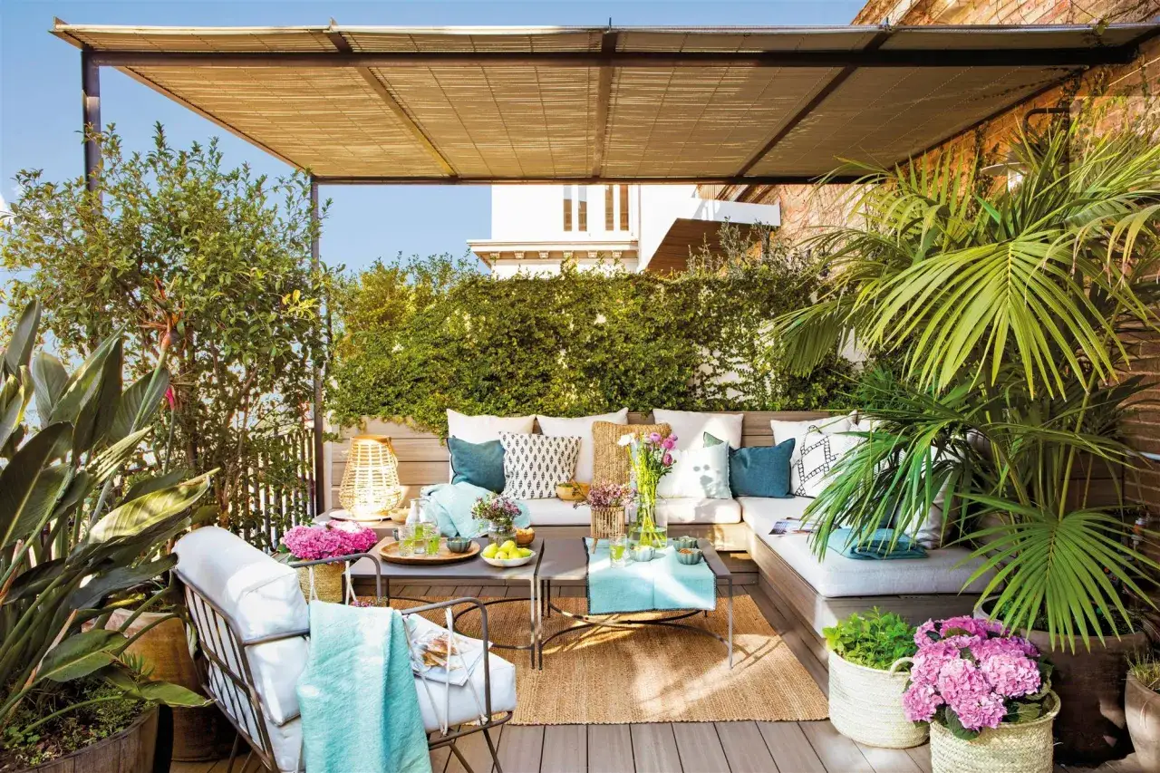 Ideas para como decorar una terraza grande: un sofá modular, mesas bajas, plantas exuberantes y cojines crean un oasis acogedor.