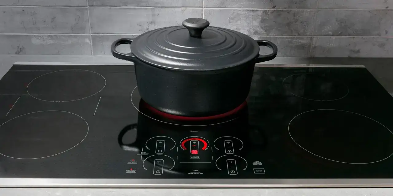 Olla negra sobre placa de inducci&oacute;n moderna. El control de 