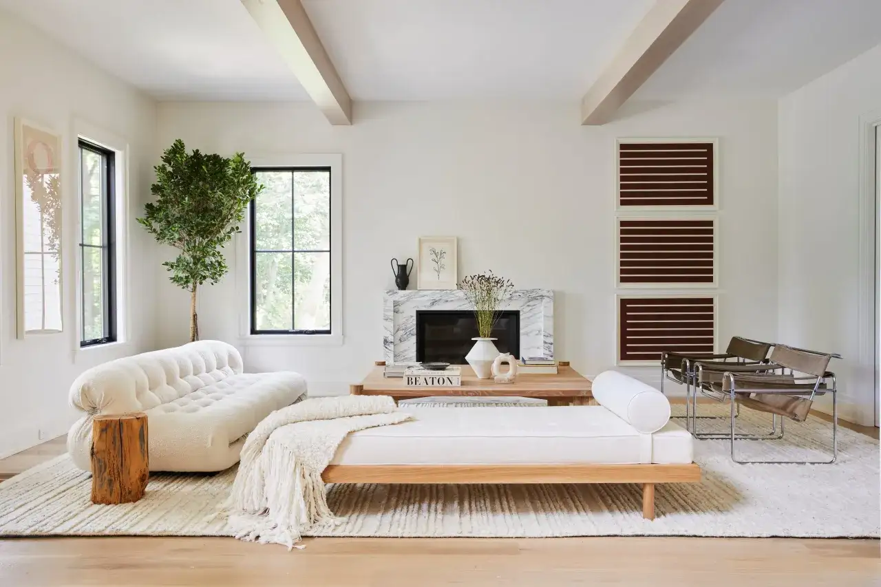 Sal&oacute;n con sof&aacute; curvo blanco, chaise longue de madera, chimenea de m&aacute;rmol y decoraci&oacute;n de estilo moderno.