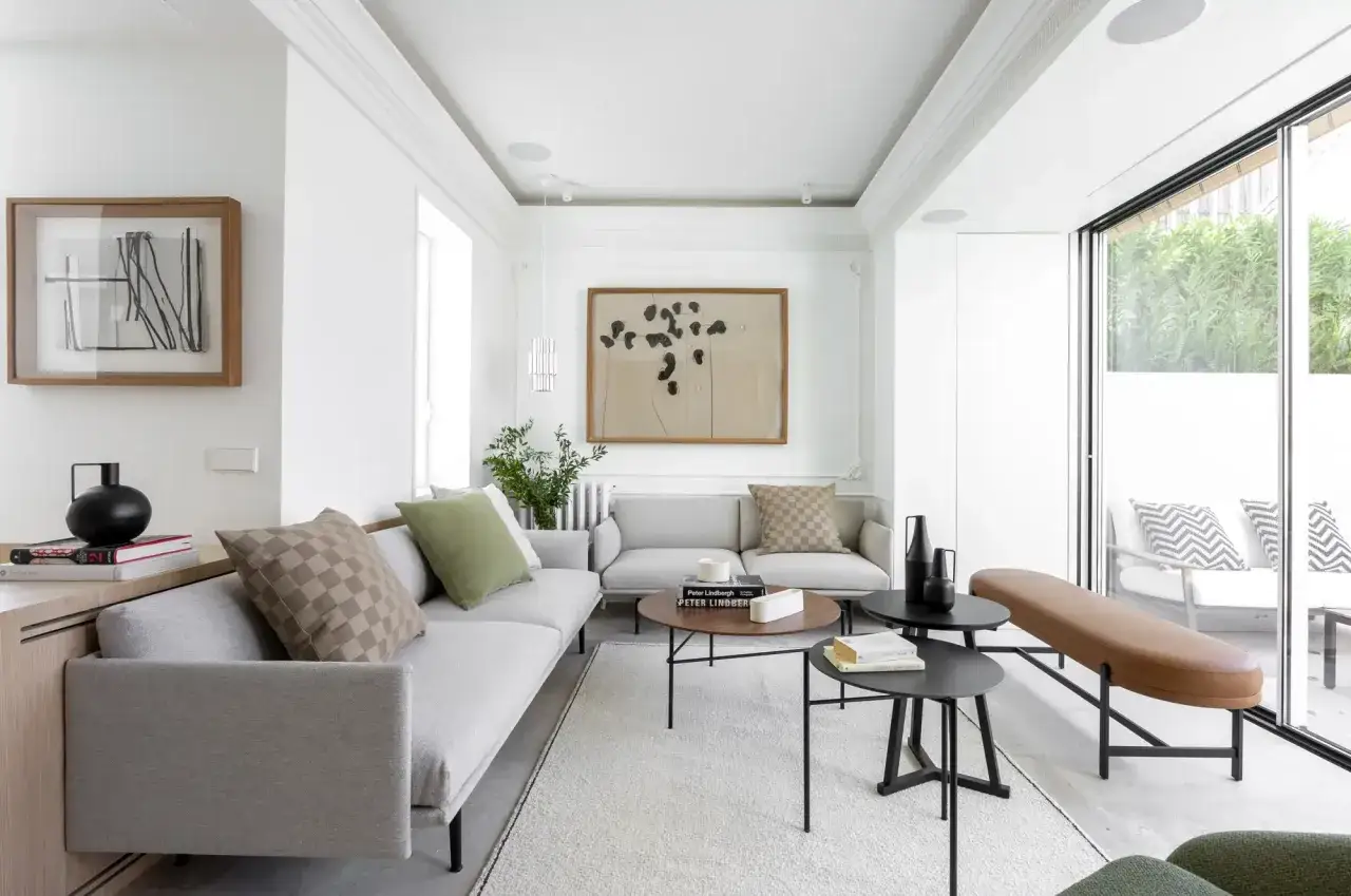Unir terraza y sal&oacute;n: un espacio luminoso con sof&aacute;s grises, mesa de centro de madera y ventanales que conectan con el exterior.