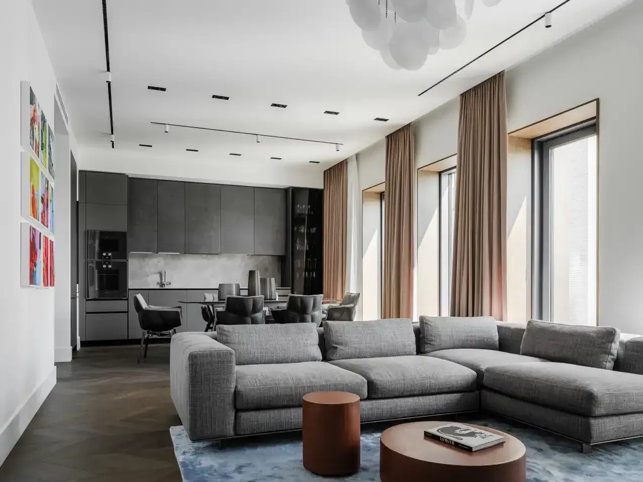 Elegante salón-comedor con sofás grises y cocina moderna. Los tonos grises para paredes interiores crean un ambiente sofisticado y sereno.
