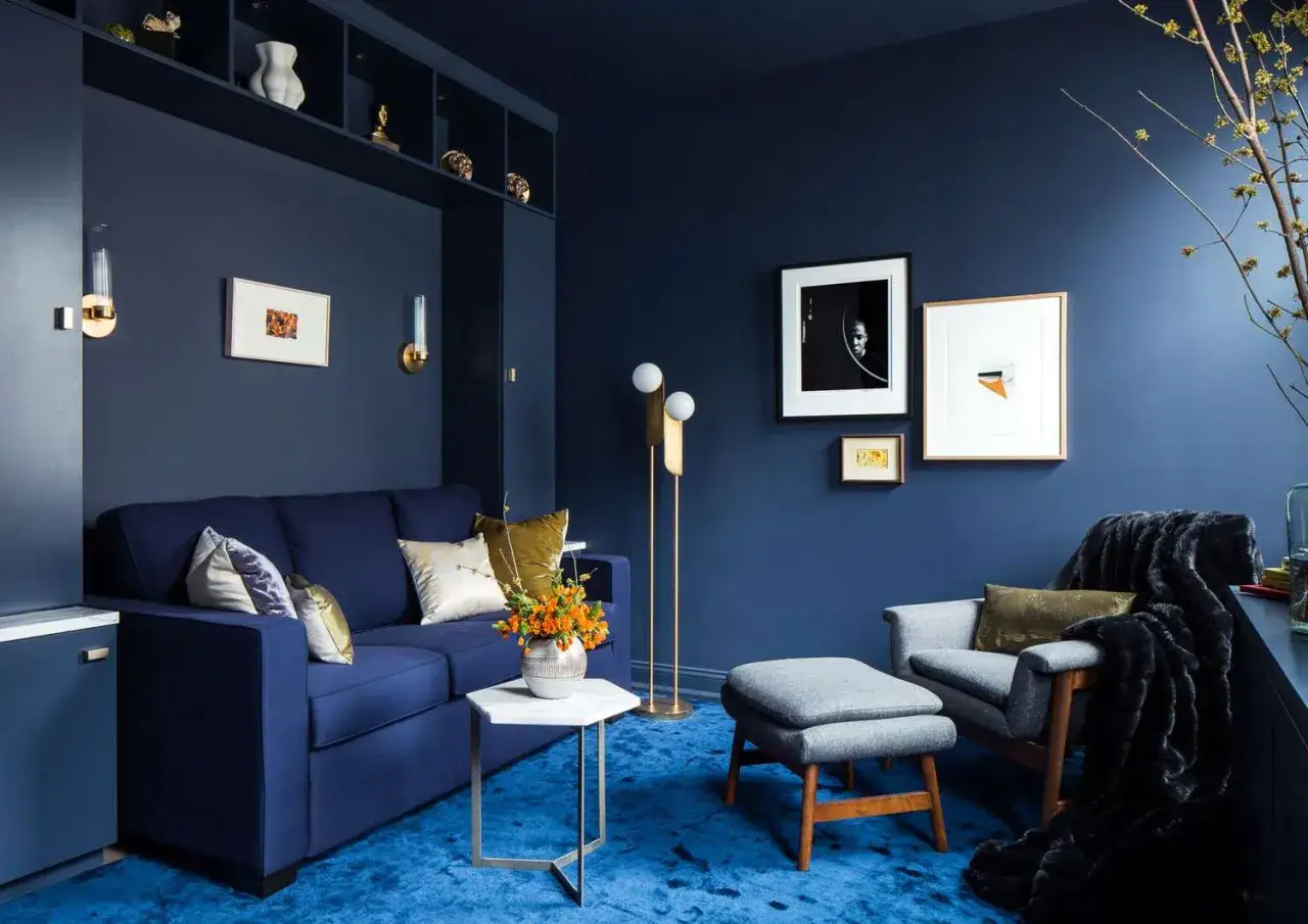 Sala azul profundo, con sofá azul, alfombra azul y acentos dorados. Aquí se exploran cuáles son los colores fríos.